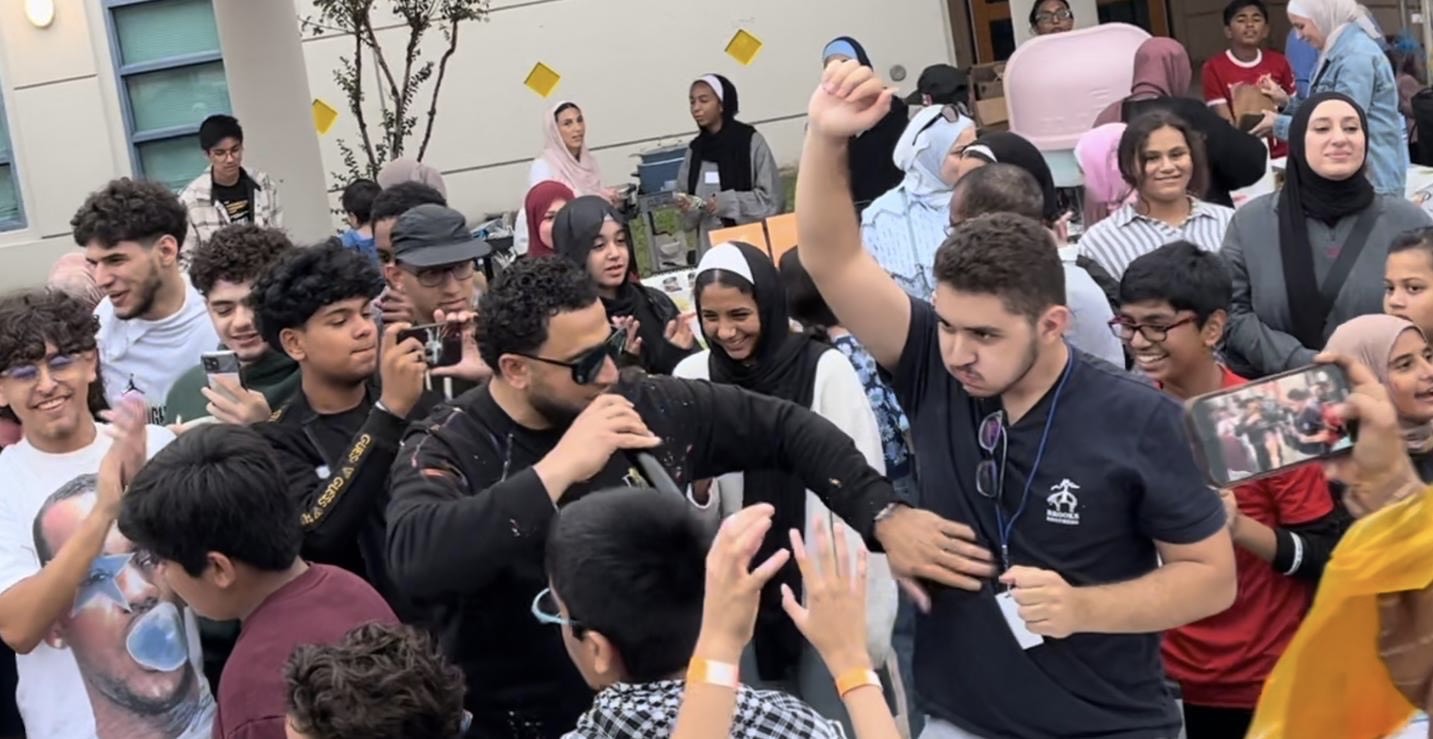 Senior, Bishr Alaqtash, celebrating with a crowd of people after winning first place at the pie eating competition. 