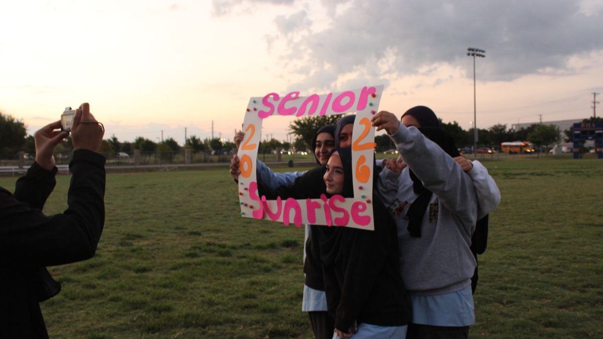 Seniors can be seen taking photos with Senior Sunrise sign.